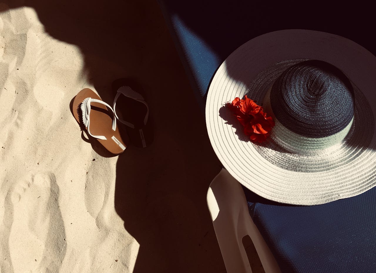 Romantic beach scene with a sun hat and flip-flops, perfect for summer vibes.